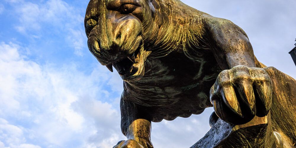 Bronzestatue des Bahkauv, der Aachener Fabelkreatur, Nahaufnahme des Kopfes vor blauem Himmel.