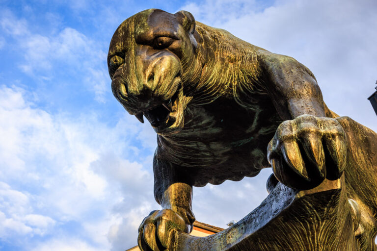 Bronzestatue des Bahkauv, der Aachener Fabelkreatur, Nahaufnahme des Kopfes vor blauem Himmel.