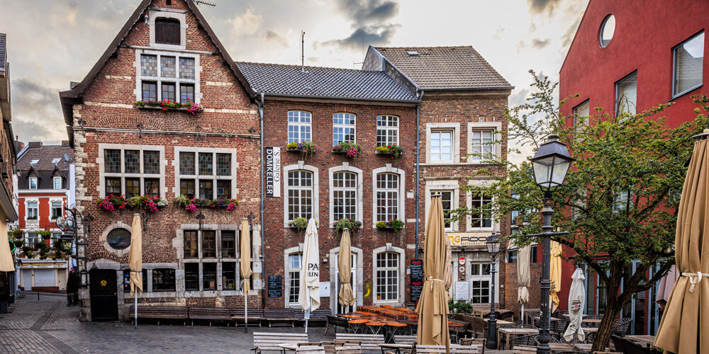 Historische Altstadthäuser mit dem Restaurant Domkeller in Aachen, Straßencafé mit Sonnenschirmen im Vordergrund.