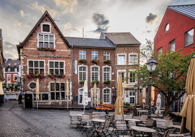 Historische Altstadthäuser mit dem Restaurant Domkeller in Aachen, Straßencafé mit Sonnenschirmen im Vordergrund.