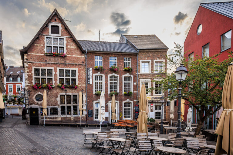 Historische Altstadthäuser mit dem Restaurant Domkeller in Aachen, Straßencafé mit Sonnenschirmen im Vordergrund.