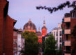 Blick durch eine Burtscheider Wohnstraße auf die rote Kuppel und den Turm der Propsteikirche St. Johann Baptist im Abendrot