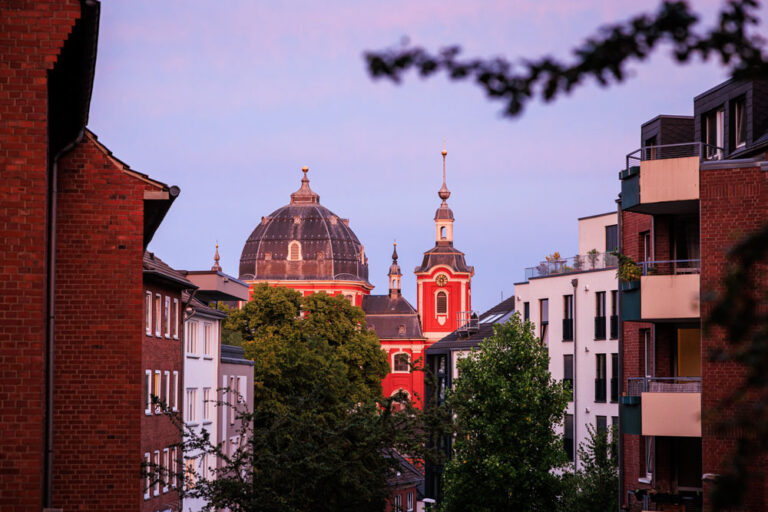 St. Johann Baptist Burtscheid im Abendlicht Blick durch eine Burtscheider Wohnstraße auf die rote Kuppel und den Turm der Propsteikirche St. Johann Baptist im Abendrot