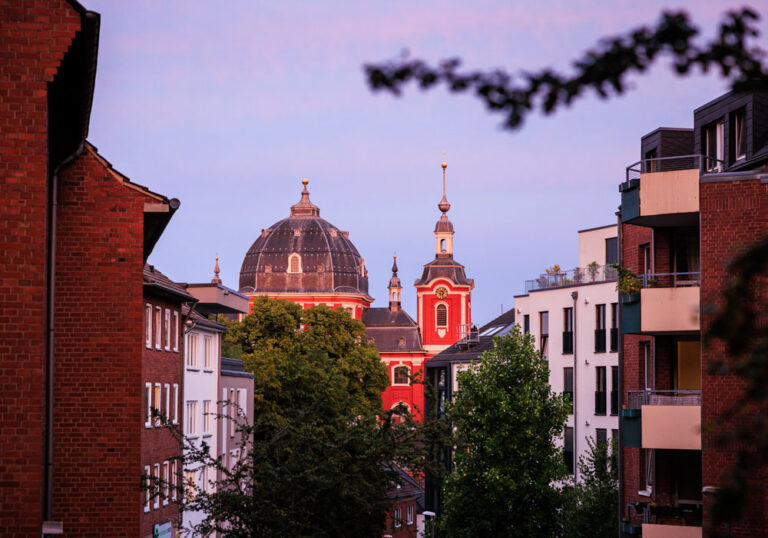 St. Johann Baptist Burtscheid im Abendlicht Blick durch eine Burtscheider Wohnstraße auf die rote Kuppel und den Turm der Propsteikirche St. Johann Baptist im Abendrot