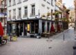 Eckhaus des Café Van den Daele in der Aachener Altstadt mit roten Sonnenschirmen und gelben Stühlen vor der Fassade