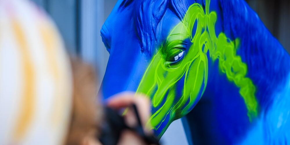 Detailaufnahme eines blau-grün bemalten Pferdemodells beim Airbrushen im Rahmen des CHIO Aachen