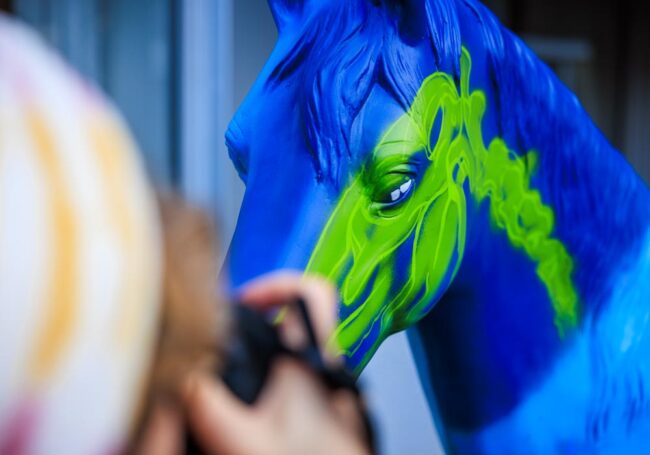 Detailaufnahme eines blau-grün bemalten Pferdemodells beim Airbrushen im Rahmen des CHIO Aachen