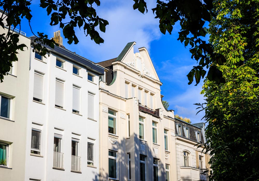 Historische Altbaufassade mit verziertem Giebel an der Pontstraße, umrahmt von Baumkronen