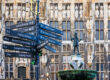 Wegweiser mit Richtungsschildern zu Aachener Sehenswürdigkeiten vor der Rathausfassade, rechts die Karlsbrunnen-Statue