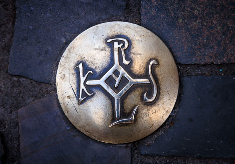 Bronzenagel mit dem Karolus-Monogramm im Kopfsteinpflaster der Aachener Altstadt