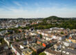 Luftaufnahme des Lousbergs mit seiner markanten grünen Kuppe über den Dächern der Aachener Innenstadt