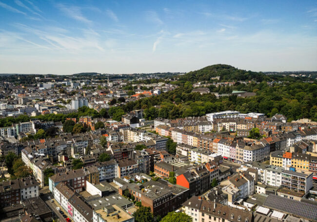 Luftaufnahme des Lousbergs mit seiner markanten grünen Kuppe über den Dächern der Aachener Innenstadt