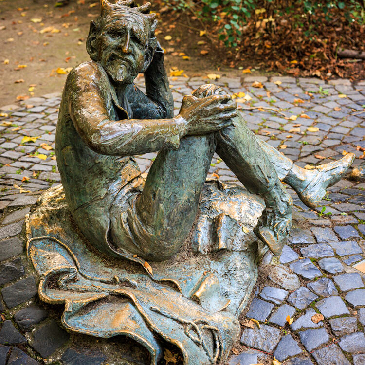Bronzestatue des Teufels aus der Lousbergsage, sitzend auf einem Sandsack am Fuß des Lousbergs