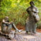 Bronzestatuen von Bauersfrau und Teufel am Denkmalplatz auf dem Lousberg, umgeben von herbstlichem Grün