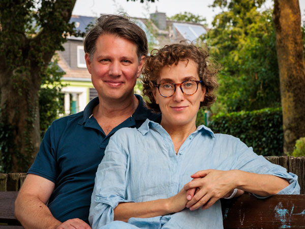 Porträtfoto von Maria und Marcus, den Gründern von Aachen Guide, sitzend auf einer Bank im Grünen