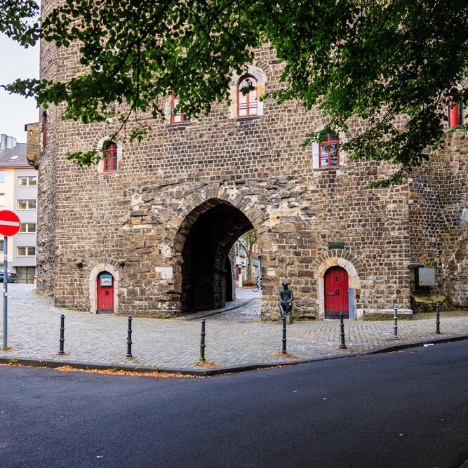Eckansicht des Marschiertors mit zwei roten Türen und einem Einfahrt-verboten-Schild, im Vordergrund die Pennsoldat-Statue