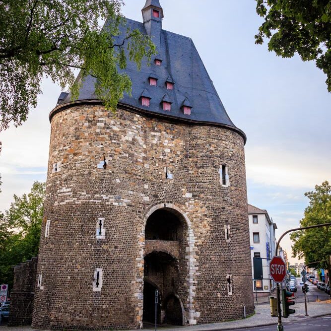 Klassische Außenansicht des Aachener Marschiertors mit Turmdach und Wetterfahne