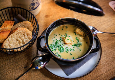 Postkutschers Kartoffelsuppe im Postwagen Zum Ratskeller, mit Schnittlauch und Croûtons, daneben ein Brotkorb mit frischem Baguette