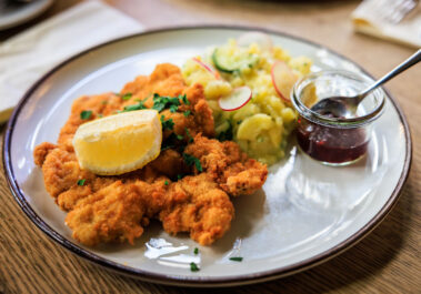 Schnitzel Wiener Art im Postwagen Zum Ratskeller mit Zitronenspalte, Petersilie, Kartoffel-Gurkensalat und Preiselbeeren im Glas