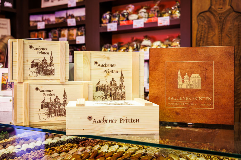 Holzkisten mit „Aachener Printen"-Aufdruck und Dom-Motiv bei Printen Klein, ideal als Geschenk oder Mitbringsel