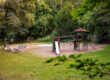 Spielplatz Buchenallee in Aachen mit Rutsche, Klettergerüst, Schaukel und Karussell, umgeben von dichtem Baumbestand