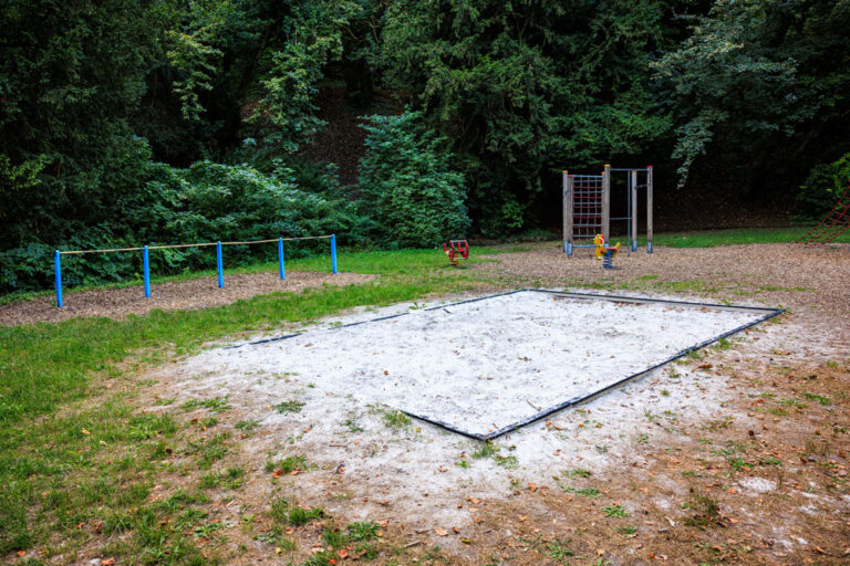 Sandspielbereich am Spielplatz Buchenallee mit Balancierbalken und Klettergerüst im Hintergrund