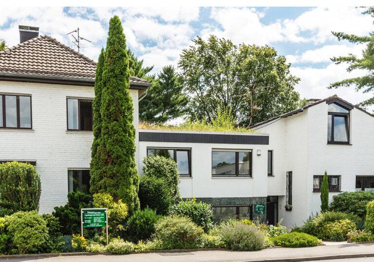 Kanzleigebäude von Steuerberater Capellmann und Partner mbB in Herzogenrath, weißes Wohn- und Bürohaus mit begrüntem Dach und gepflegtem Vorgarten
