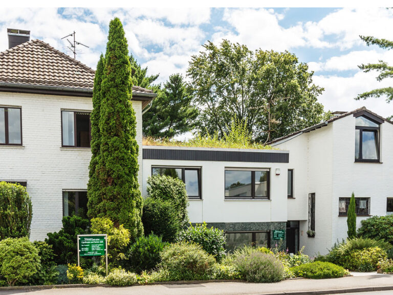 Kanzleigebäude von Steuerberater Capellmann und Partner mbB in Herzogenrath, weißes Wohn- und Bürohaus mit begrüntem Dach und gepflegtem Vorgarten