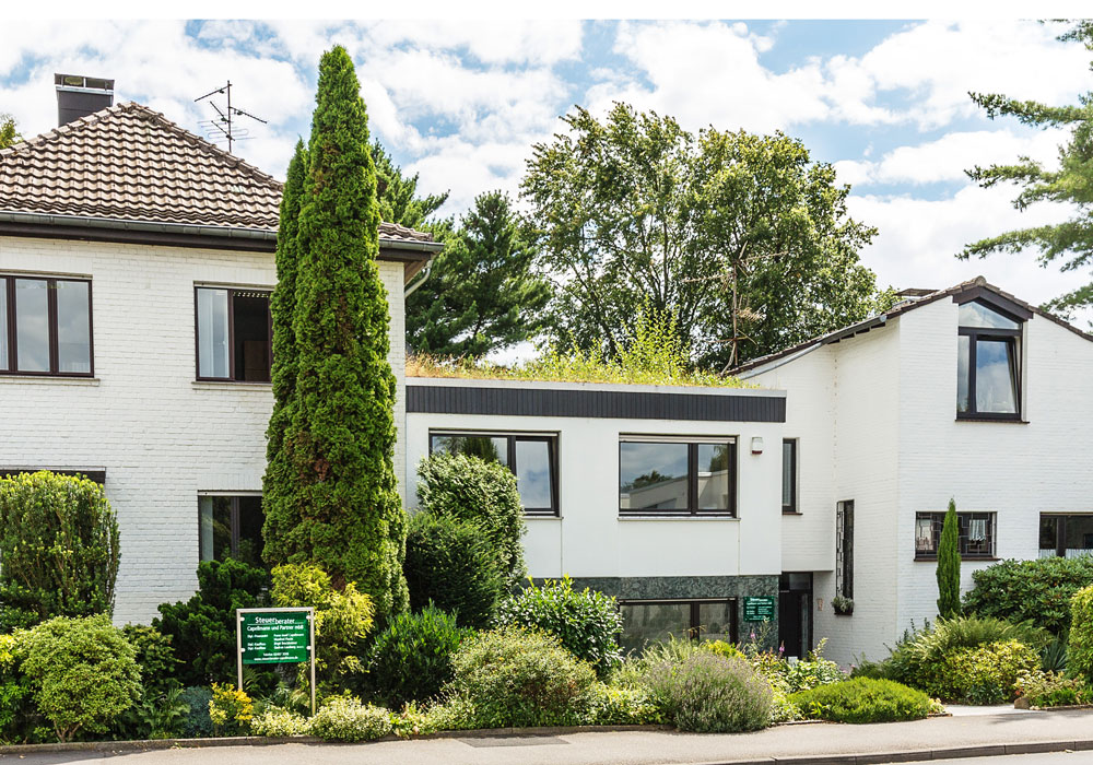 Kanzleigebäude Capellmann und Partner Kanzleigebäude von Steuerberater Capellmann und Partner mbB in Herzogenrath, weißes Wohn- und Bürohaus mit begrüntem Dach und gepflegtem Vorgarten