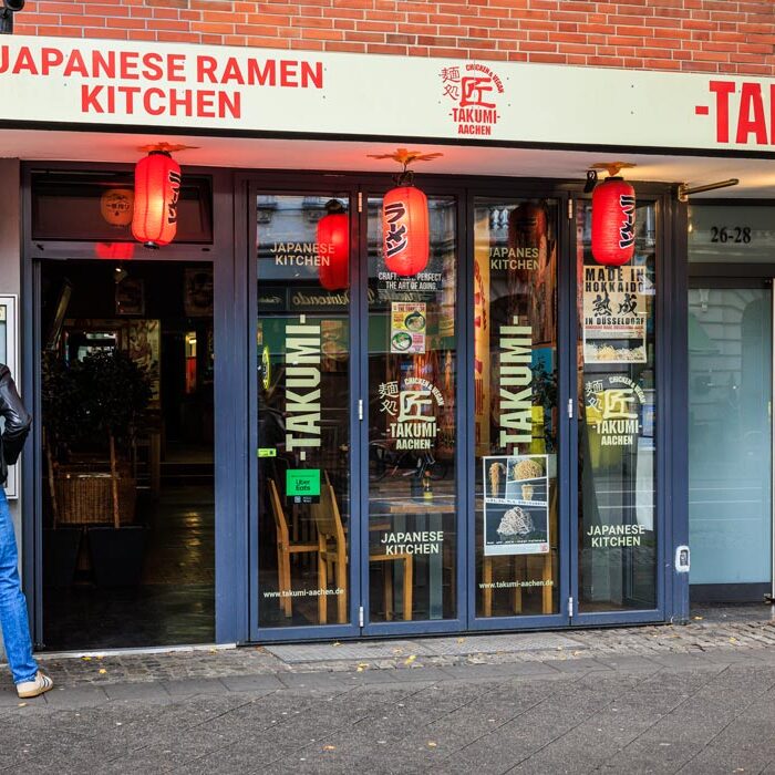 Außenfassade von Takumi Aachen Chicken & Vegan mit rotem Schriftzug „Japanese Ramen Kitchen" und roten Laternen am Eingang