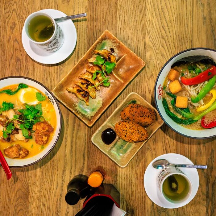 Tisch von oben fotografiert bei Takumi Aachen mit Creamy White Tan Tan Men, Vegan Miso Ramen, Gyoza, Süßkartoffel-Kroketten und zwei Tassen grünem Tee