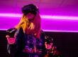 Spielerin mit VR-Brille und Controllern in magentafarbenem Licht im Blauwal VR-Café Aachen