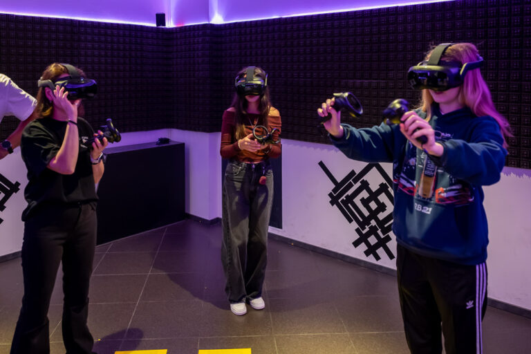 Drei Spielerinnen mit VR-Headsets und Controllern in der Spielarena des Blauwal VR-Cafés Aachen
